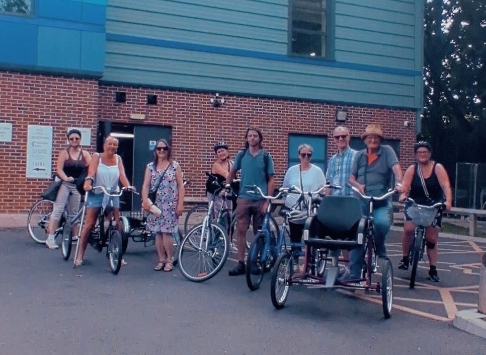 small group of people standing with bikes outside a building in a park