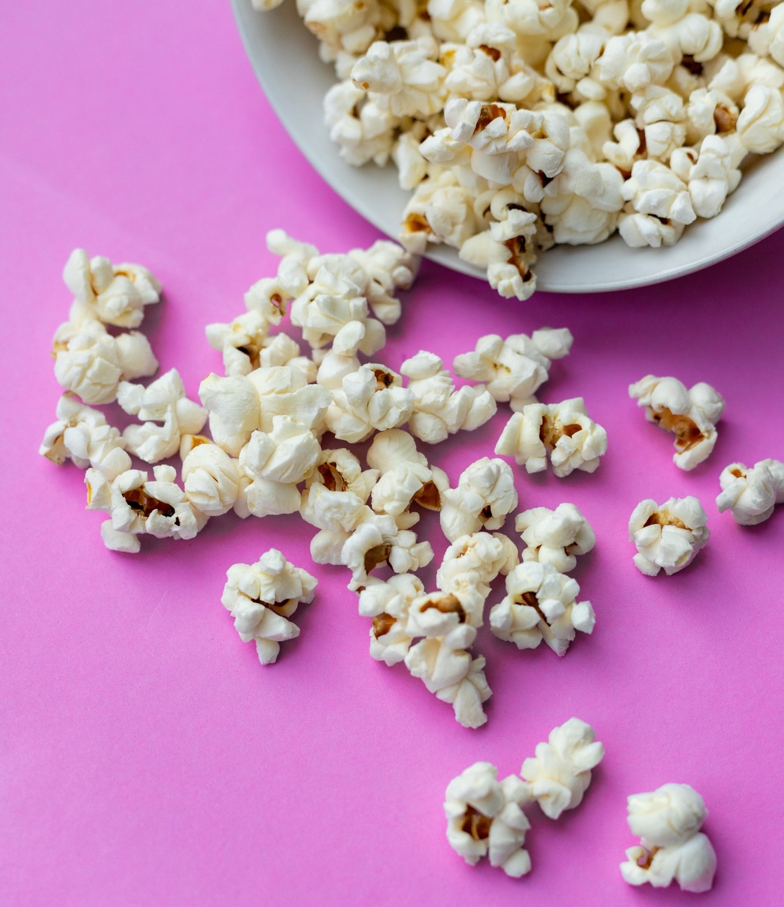 Cinema popcorn spilling out over a pink background