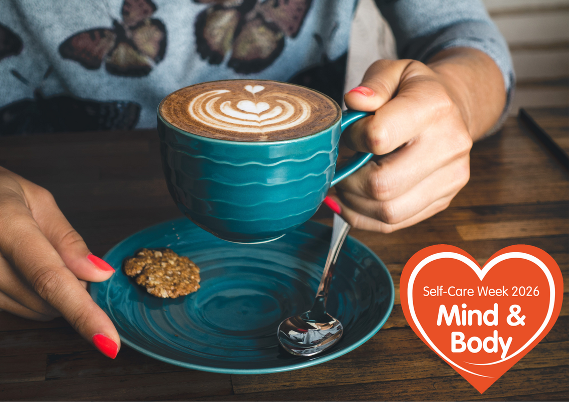 close up of hands holding coffee, sat at a table