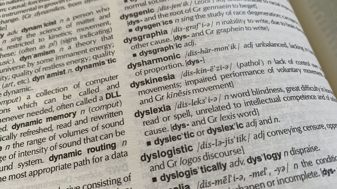 An dictionary open to the letter 'D' and showing the definition of the word 'dyslexia' among other words