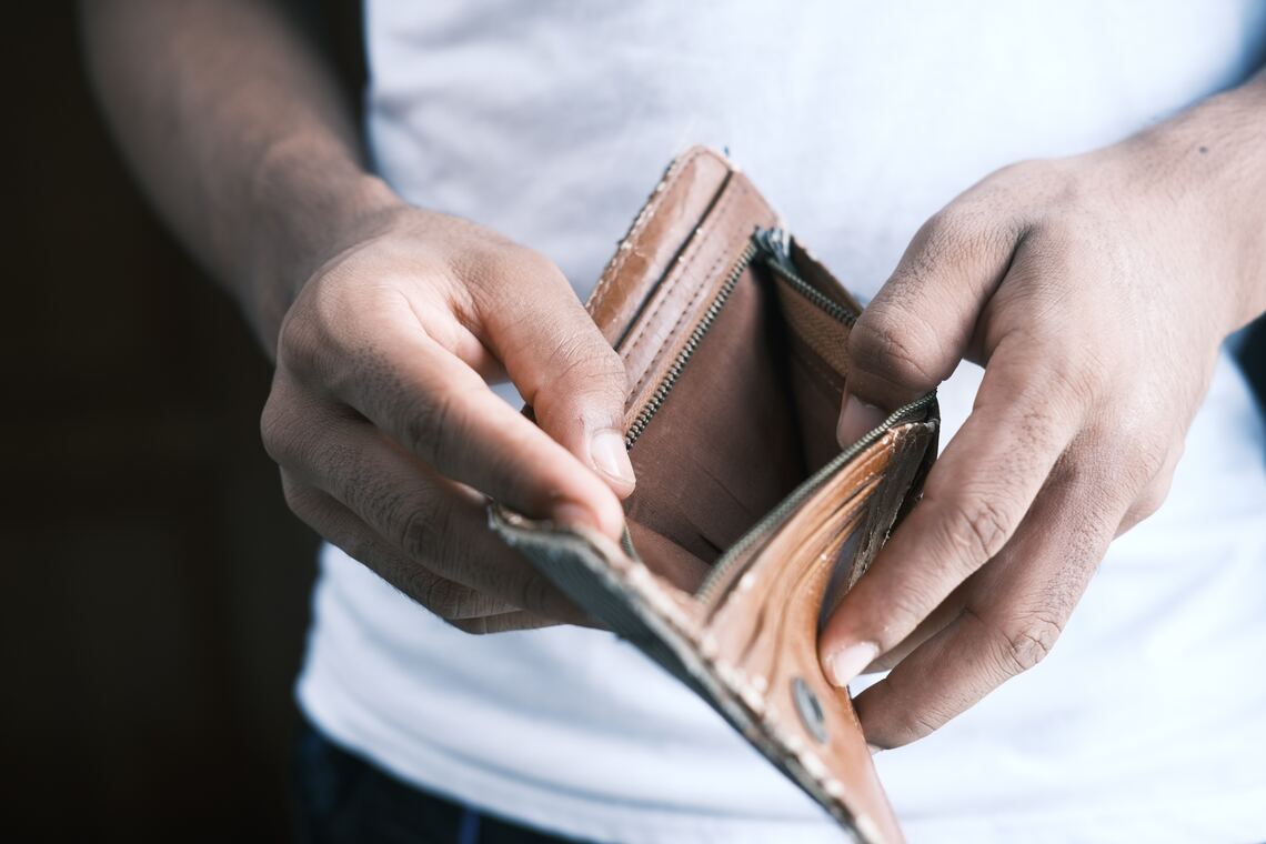 A man holding a leather wallet that is completely empty on the inside