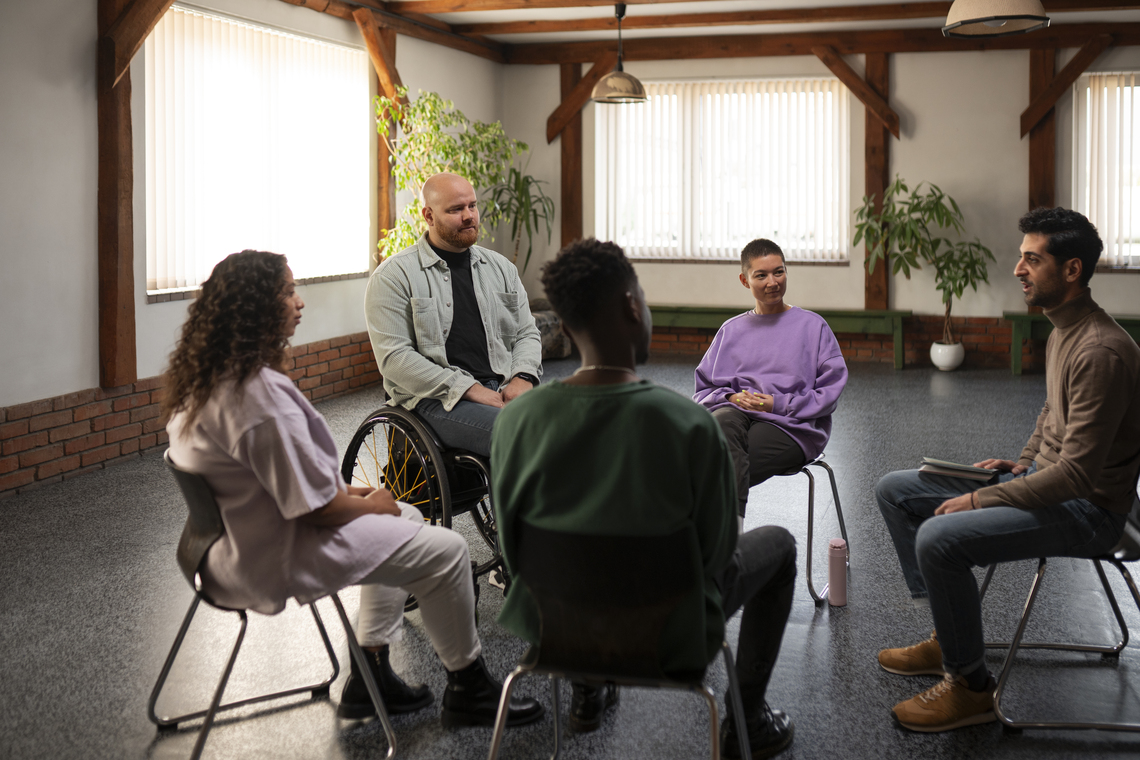 A group of people talking while sat down on a chairs in a circle