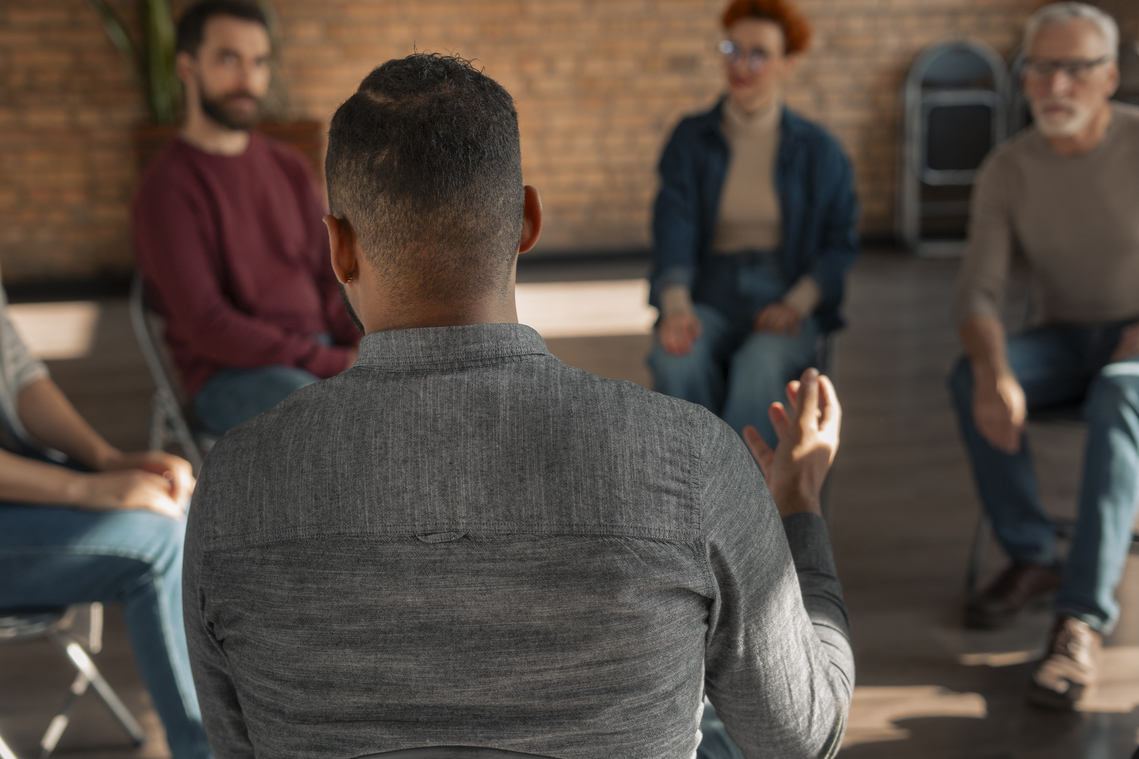 A group of people talking while sat down on a chairs in a circle