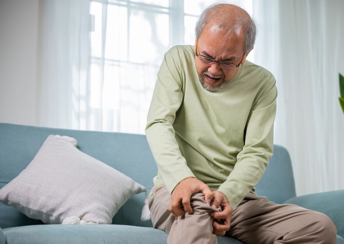 Older man holds his knee in pain