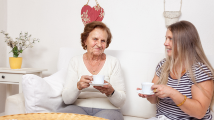 2 women sat on a sofa enjoying a cup of tea 
