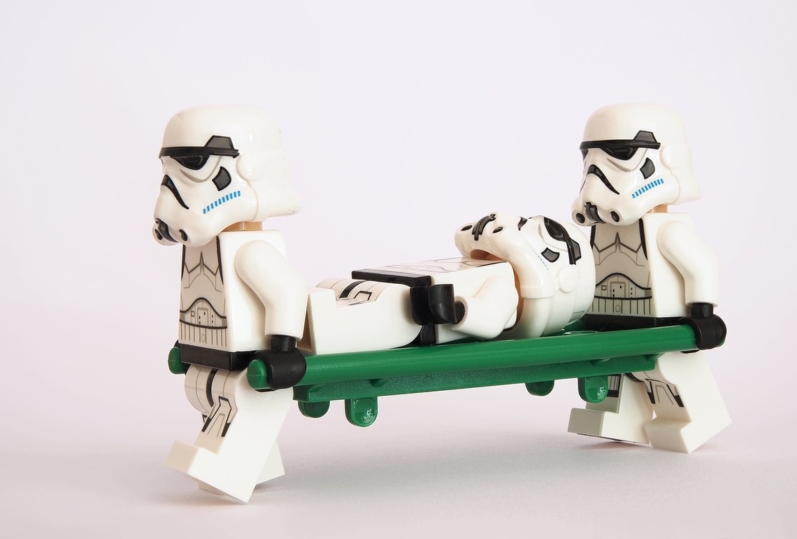 Two Lego Stormtroopers carrying a third Stormtrooper on a Lego Stretcher