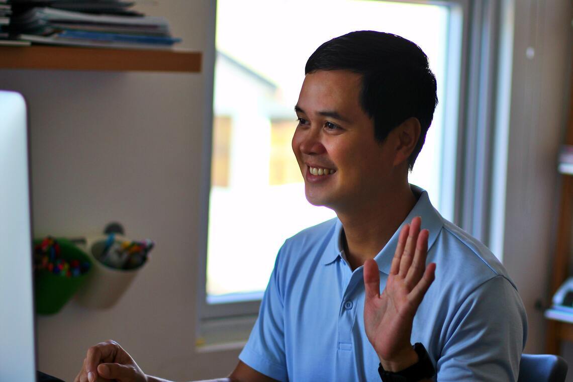 Man looking at computer screen and waving 